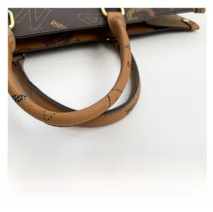 Close-up of contrast leather handle and golden metal rings on minimalist tote bag