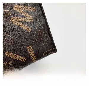 Macro shot of dark brown pebbled leather texture with ANWEI logo on the tote bag
