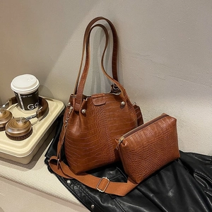 Detailed view of brown crocodile texture bucket bag and matching pouch with shoulder strap