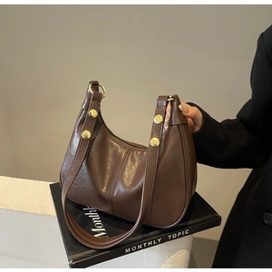 Détail d'un sac à bandoulière marron foncé vintage en cuir brillant avec rivets dorés