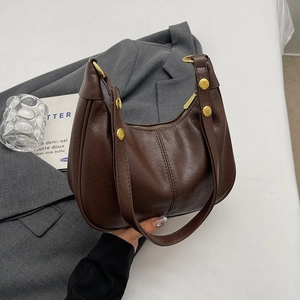 Détail du sac demi-lune marron foncé vintage avec coutures et rivets dorés