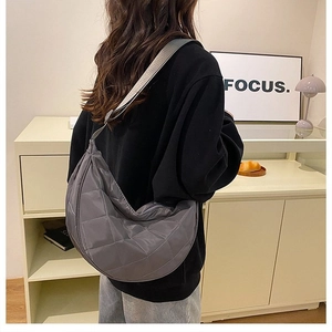 Vista posteriore della modella con borsa a mezzaluna grigia trapuntata a rombi in nylon