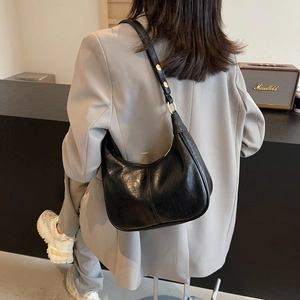 Détail d'un sac sous le bras en cuir noir avec boucles dorées et broderie élégante