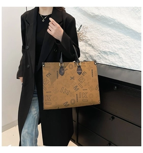 Detailed side view of a brown tote bag with letter prints and long black handles