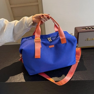 Blue nylon travel tote with orange handles and shoulder strap for outdoor lifestyle