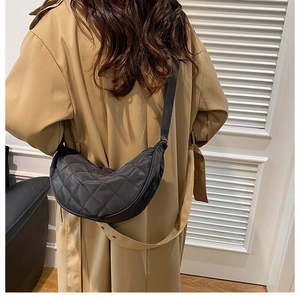 Borsa a tracolla trapuntata a mezzaluna nera indossata su un trench beige chiaro