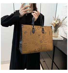 Detailed close-up of textured tote bag with contrast piping and golden hardware