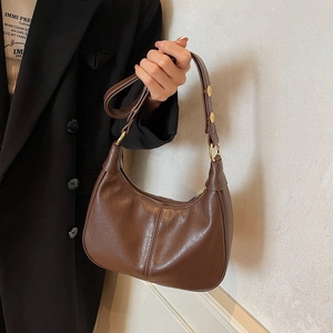 Détail d'un sac hobo vintage en cuir marron avec coutures verticales et boucles en bronze