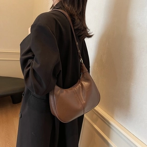 Vue détaillée latérale d'un sac Hobo marron foncé porté avec un blazer noir