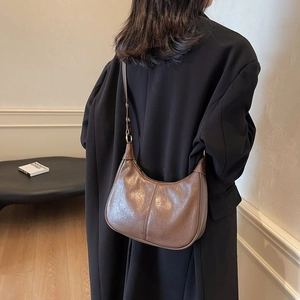 Détail d'un sac porté épaule demi-lune marron avec couture verticale et sangle réglable