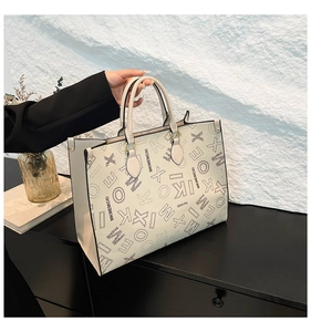 Detail view of large cream tote bag featuring black graffiti letters and firm handles
