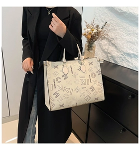 Detail of beige tote bag featuring black letter print and contrast stitching