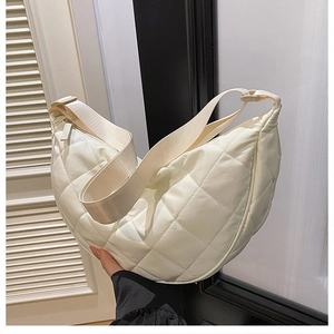 Dettaglio della borsa a mezzaluna trapuntata beige con tracolla larga e rombi