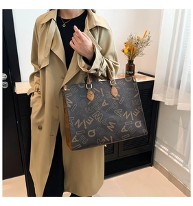 Detail of a large brown tote bag with letter print and premium leather shoulder strap