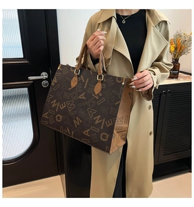 Detail view of the brown leather tote bag showing color-block design and gold hardware