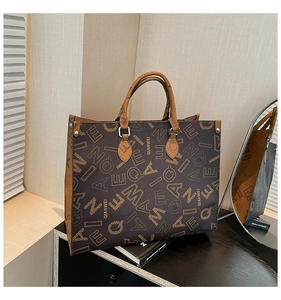 Detail of reinforced tote handles and vintage monogram pattern on high-quality leather