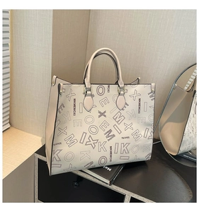 Detailed close-up of beige tote bag with chic contrast stitching and letter print