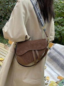 Detail of dark brown saddle bag featuring suede contrast and lettered wide strap
