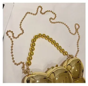 Vue détaillée d'un sac doré brillant avec poignée à grosses perles et bandoulière