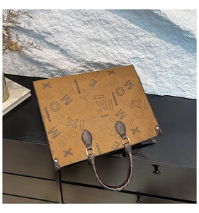 Detail of vintage brown tote bag with monogram print and gold hardware on black wood