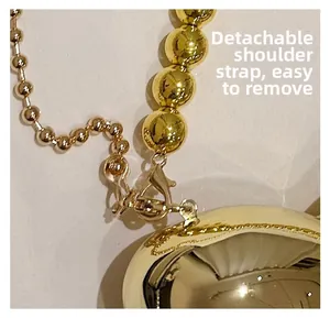 Détail de la bandoulière amovible en perles dorées et du fermoir mousqueton du sac