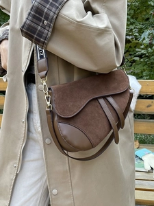 Detail of vintage dark brown saddle bag with suede texture and wide branded strap