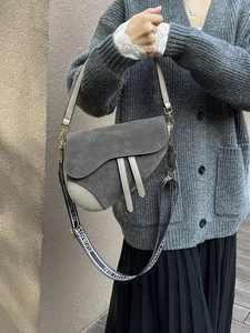 Close-up of grey saddle bag with suede texture and patterned jacquard wide strap