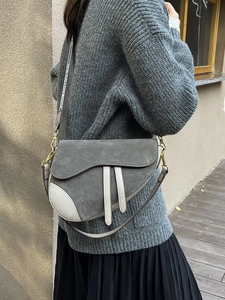 Detail of grey suede and cream leather saddle bag with vintage gold metal hardware buckle