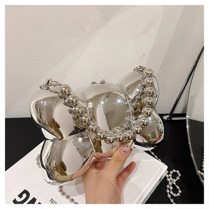 Détail du sac papillon argenté avec finition miroir métallique et poignée en perles