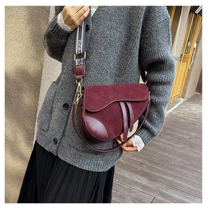 Detail of burgundy saddle bag with wide jacquard shoulder strap and suede splicing texture