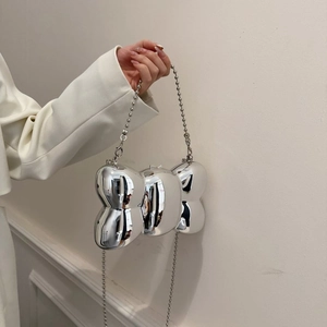 Détail du sac à main argenté métallique en forme de nœud avec bandoulière à billes
