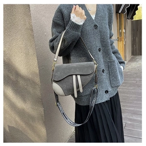 Close-up of saddle shoulder bag with grey matte finish and wide patterned strap detail