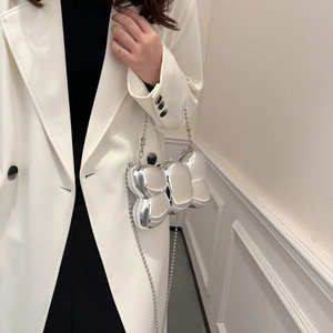 Gros plan d'un sac papillon argenté à effet miroir avec une bandoulière en chaîne billes
