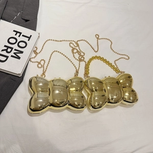 Détail du sac de soirée nœud doré avec finition miroir et poignée en perles