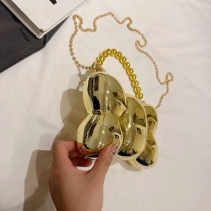 Détail du sac de soirée en métal doré en forme de pétale avec poignée perlée
