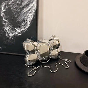 Gros plan du sac argenté en forme de nœud avec chaîne à perles sur table noire