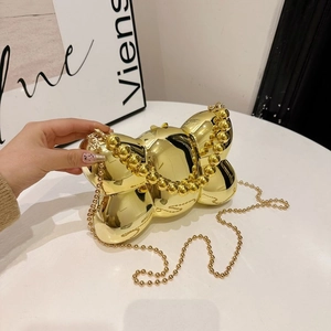 Détail du sac à main nœud doré métallisé avec poignée perlée et bandoulière chaîne