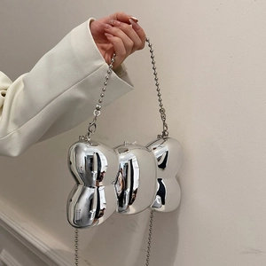 Détail d'un sac de soirée argenté en forme de nœud avec une finition métallique brillante