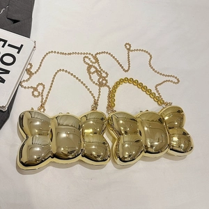 Vue détaillée du sac de soirée doré en forme de nœud avec finition miroir poli