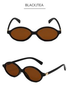 Detail view of oval black frame glasses with tea lenses and golden hinge accents