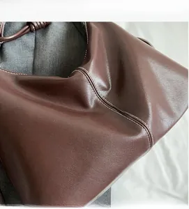 Close-up of a brown leather tote bag featuring soft texture and white contrast stitching