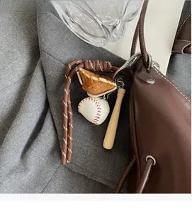Detail view of baseball glove charm with mini bat and ball on a brown tote bag