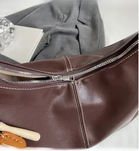 Detail of dark brown leather tote with white stitching and silver metal zipper