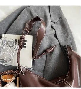 Detail of dark brown hobo bag with contrast stitching and baseball themed charms