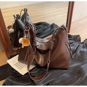 Detail of dark brown tote bag with decorative rope knot and baseball glove charm