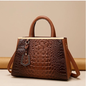 Detail of brown crocodile pattern embossed leather texture and smooth strap on handbag