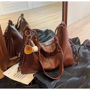 Detailed side view of a brown leather crescent hobo bag featuring a baseball theme charm
