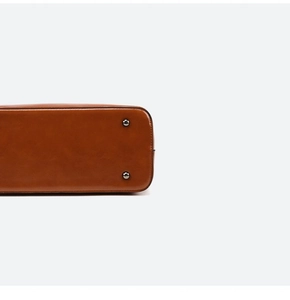 Detailed close-up of brown leather bag bottom with silver protective metal feet studs