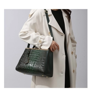 Dark green croc-embossed tote bag styled with a beige trench coat for a chic office look