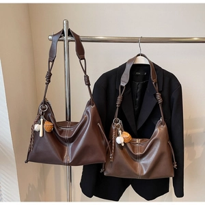 Detail of soft leather tote bags in brown shades with contrast stitching and charms